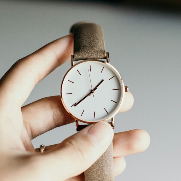 Klassische Uhr mit weißem Zifferblatt in der Hand