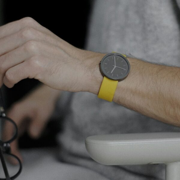Herrenuhr mit gelbem Armband am Handgelenk